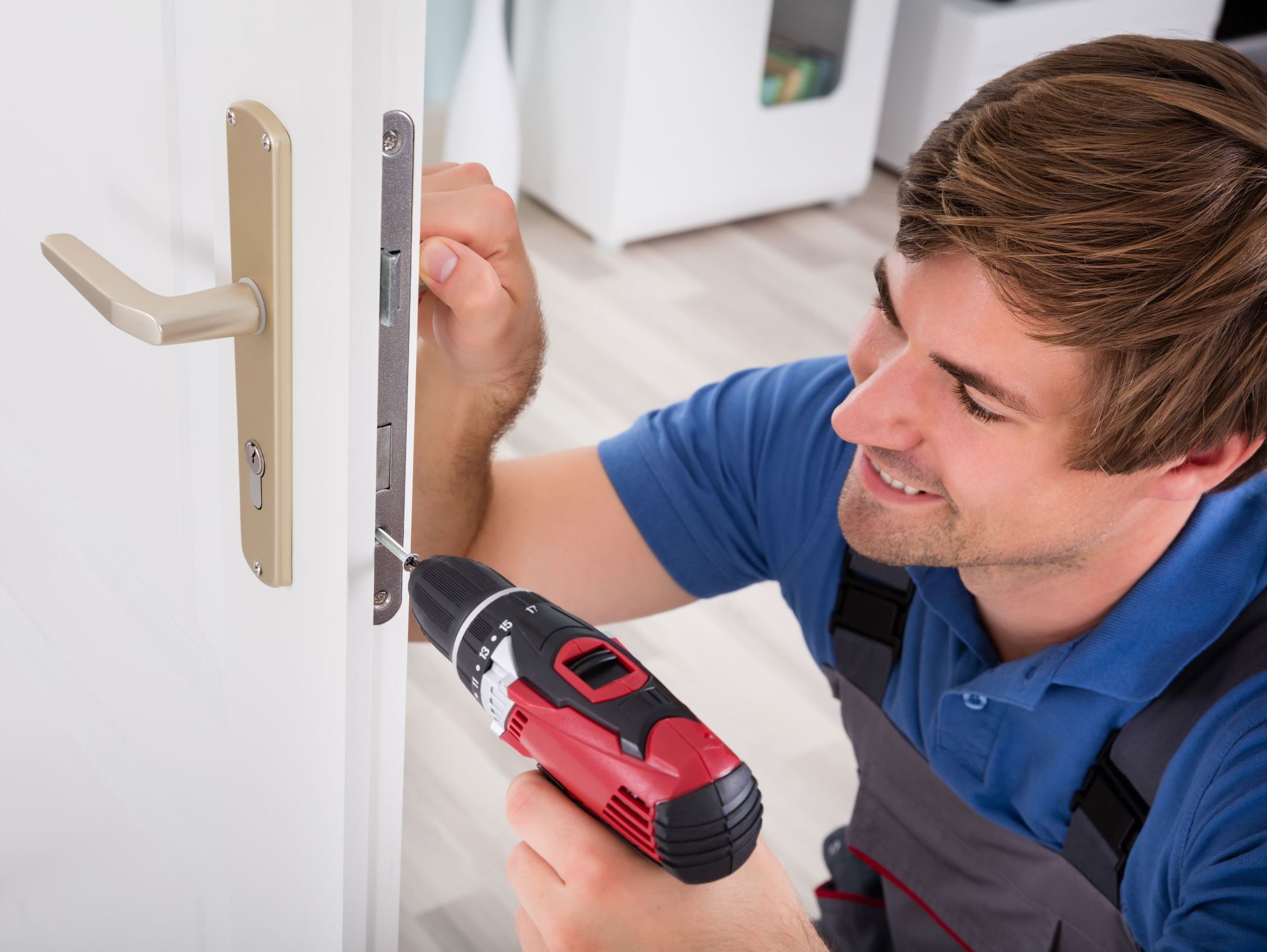 Locksmith screwing lock on door